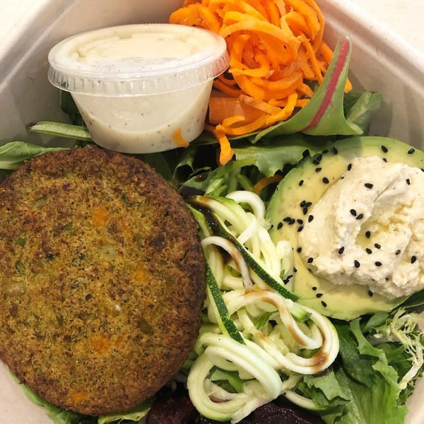 Leaf and Ginger's healthy salad with a veggie patty, avocado, hummus, zucchini noodles, and shredded carrots.